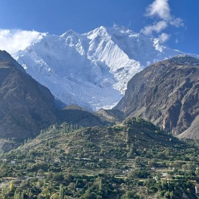 Lush green Fairy Meadows with Nanga Parbat in the background under a clear blue sky.