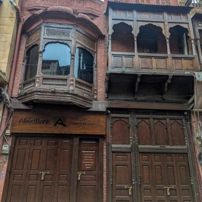 Historic wooden balconies above Allied Bank branch in urban Lahore setting