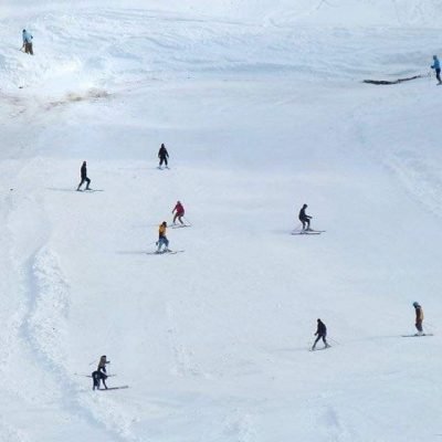 Skiers descending snowy slope at Malam Jabba Ski Resort with promotional banner at summit