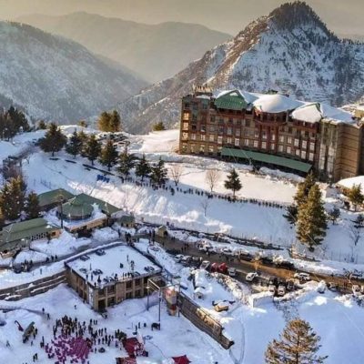 Snow-covered resort and village with people and vehicles in a mountainous winter landscape